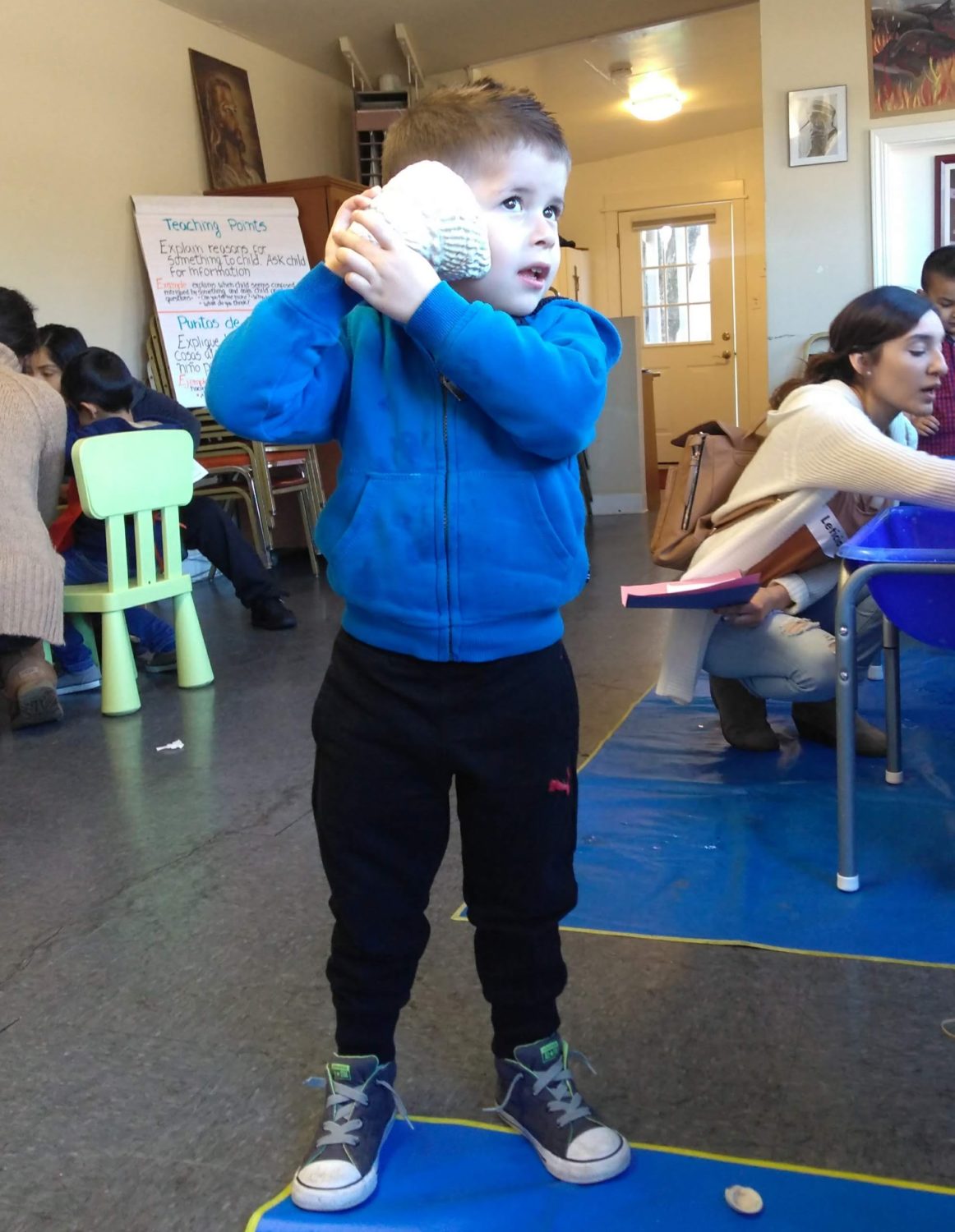 A child is actively performing a physical fitness exercise indoors, with their elbows joined together in a blue position.