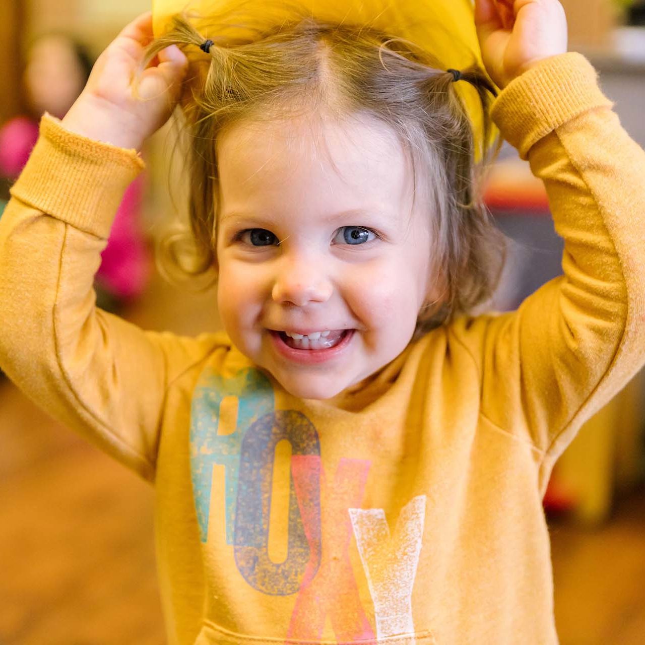 image of smiling toddler girl with hands in the air